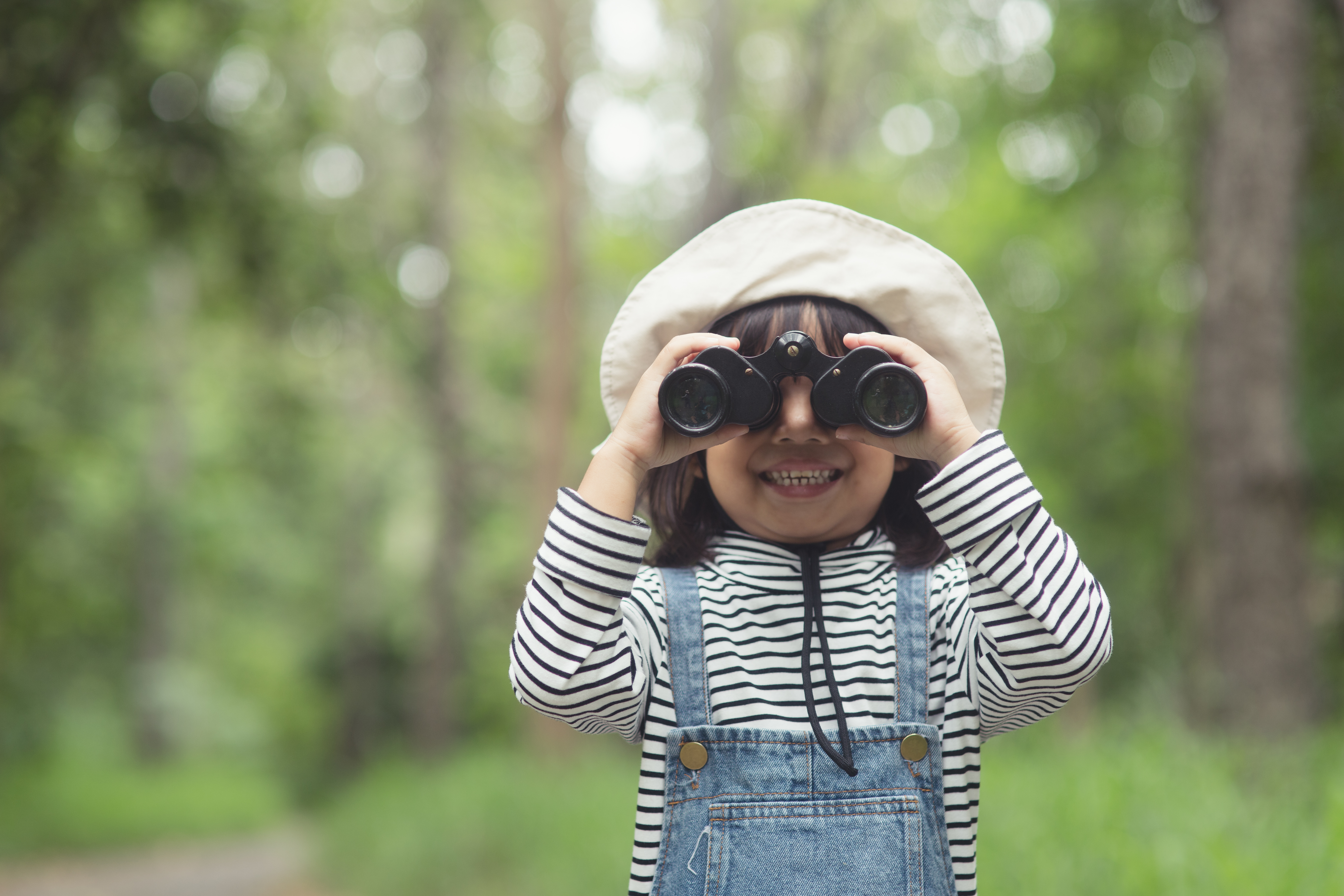 Happy kid looking ahead. Smiling child with the binoculars. Travel and adventure concept.