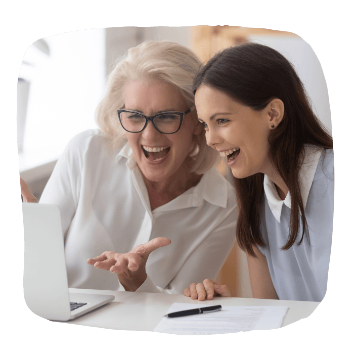 Two women looking at a laptop and smiling, excited